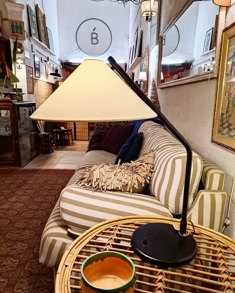 Racó de Casa Barceló amb un llum de peu vintage i un sofà de ratlles